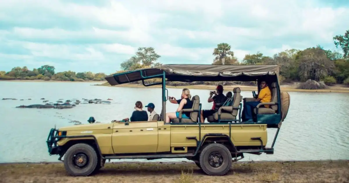 Safari vehicle beside a hippo pool in Mikumi National Park on a fly-in day trip from Zanzibar